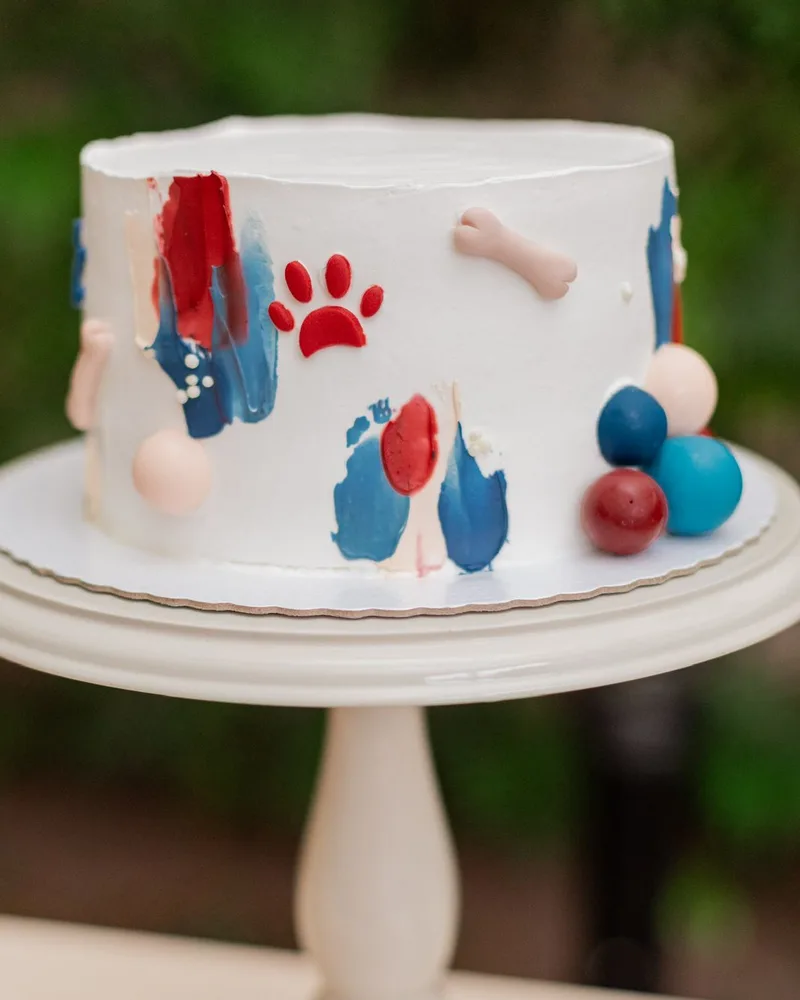 Bolo de aniversário tema cachorrinho com pinceladas azuis e vermelhas em boleira branca