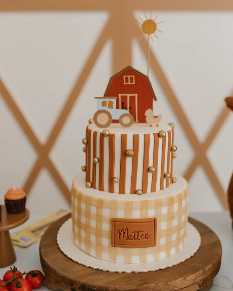 Bolo de aniversário de dois andares tema fazendinha com trator, celeiro e detalhes xadrez