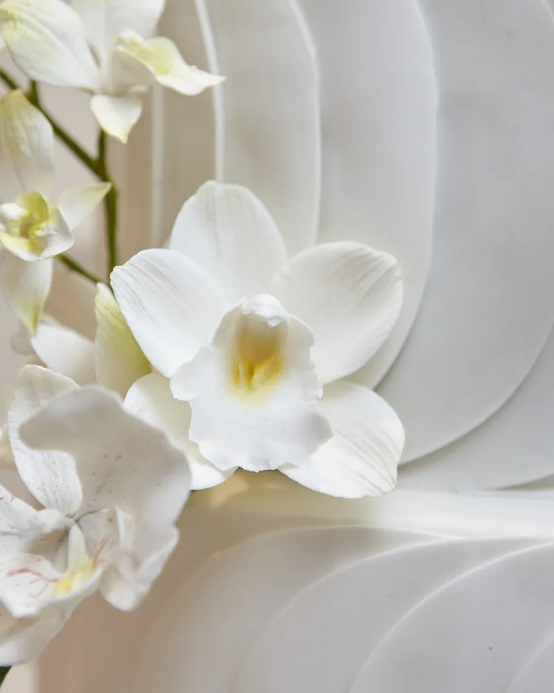 Orquídea de açúcar artesanal sobre a textura de arcos do bolo de casamento