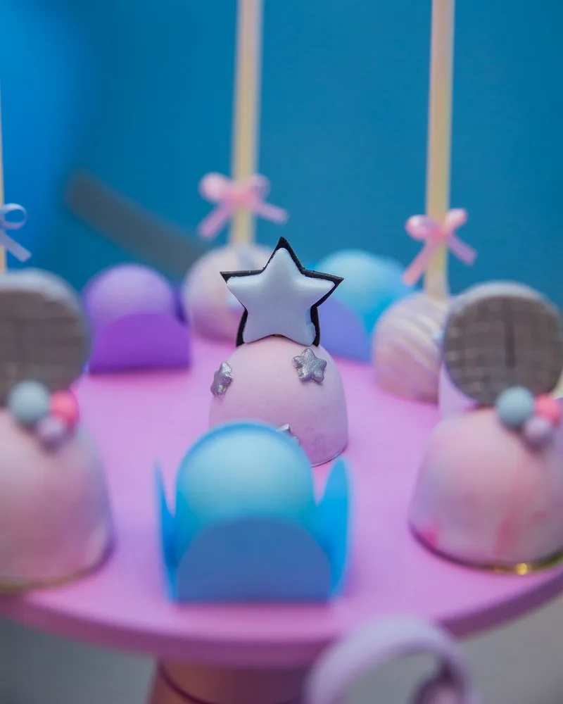 Cake pops em tons pastel com estrelas de açúcar em mesa de festa rosa e azul