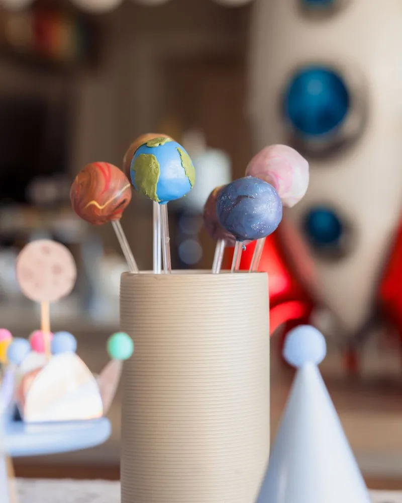 Cake pops de planetas em copo canelado para festa tema espacial
