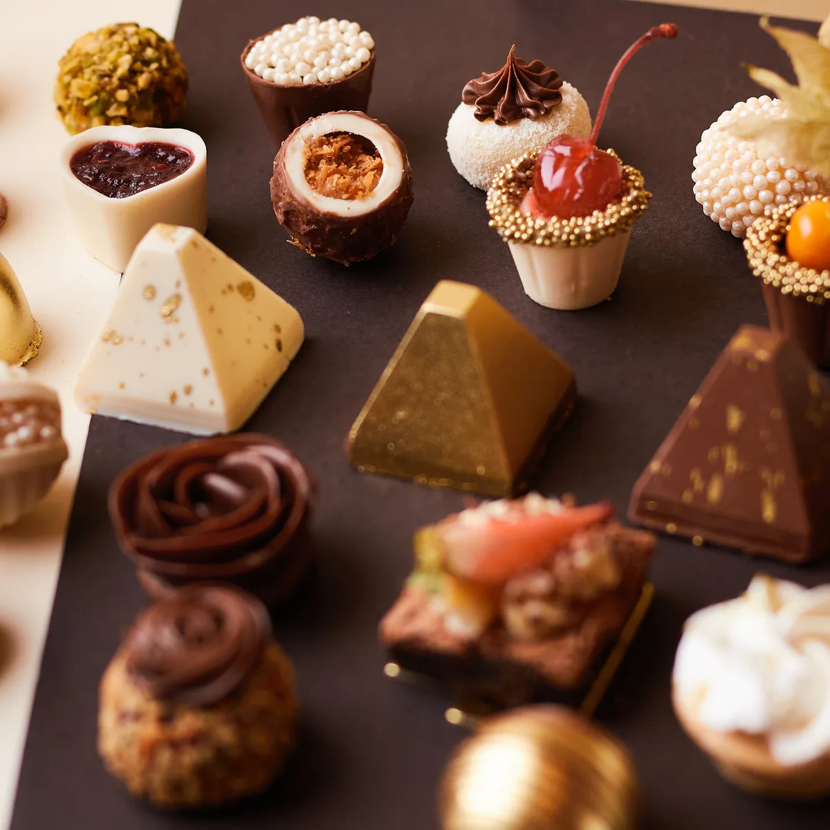 Mesa de doces finos sortidos da Momento Cake com bombons dourados, trufas e mini tortas